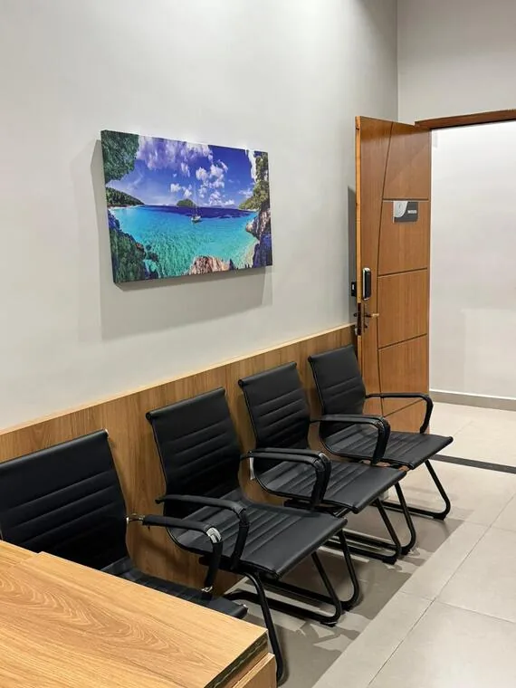Sala de espera do cartório com cadeiras alinhadas e quadro de paisagem de praia