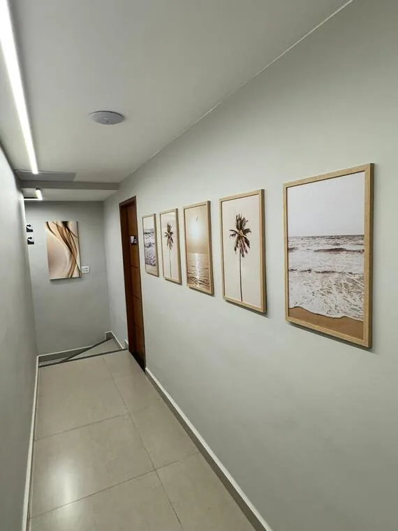 Corredor interno do cartório decorado com quadros de praia em tons claros