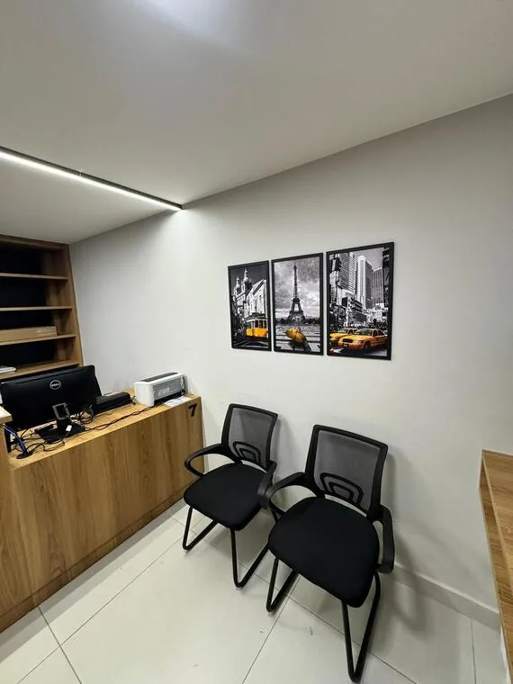 Sala de atendimento do cartório com computador e quadros de cidades em preto e branco