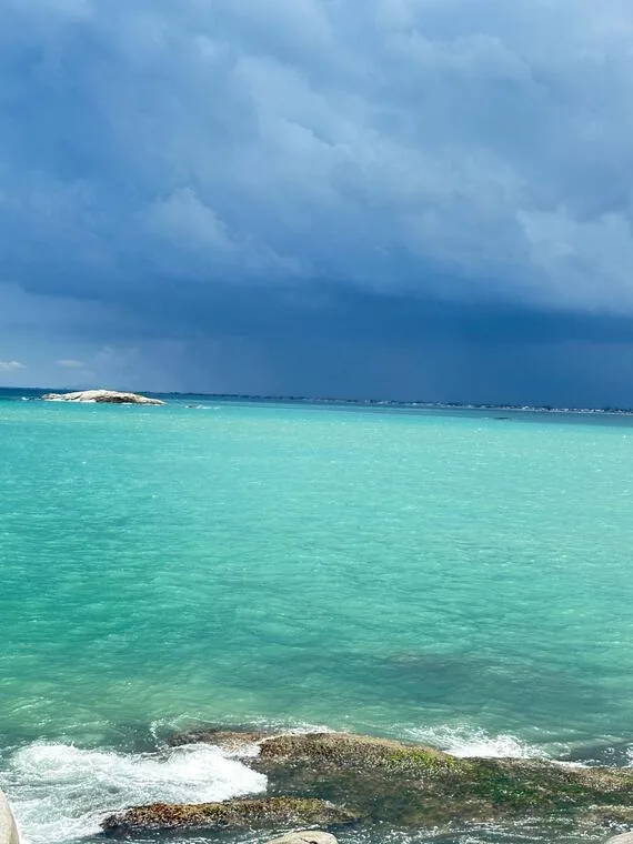Mar turquesa de Rio das Ostras contrastando com céu escuro carregado de chuva