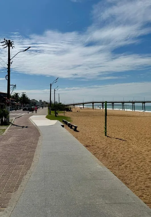 Calçadão à beira-mar de Rio das Ostras com píer sobre a praia ao fundo