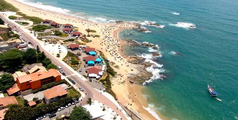 Vista aérea de praia movimentada em Rio das Ostras com quiosques e faixa de areia