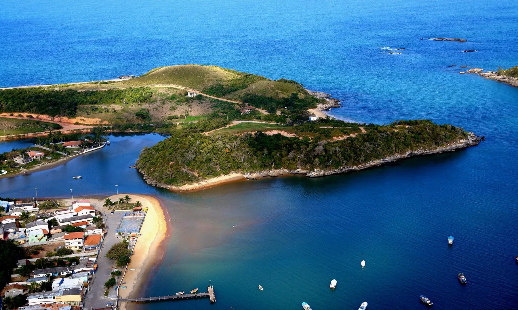 Vista aérea do encontro do rio com o mar em Rio das Ostras, com morro coberto de mata